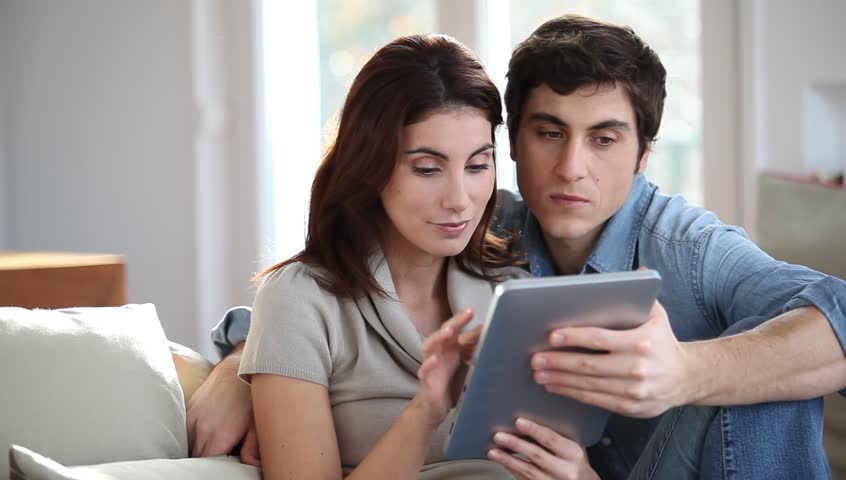Couple sitting on sofa with touchpad 