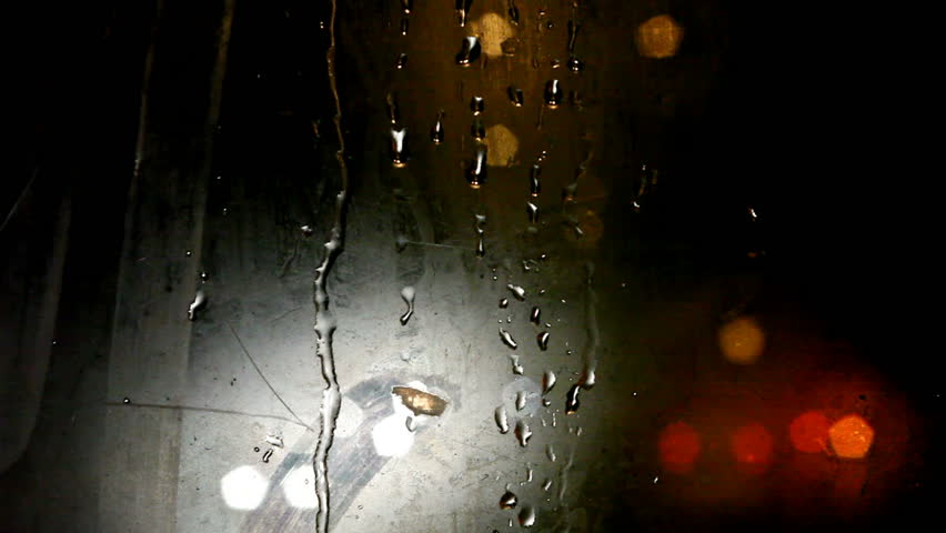 Tram's steamy  rear window view. Cold weather cityscape. Night time. Focus on window. Fading out colored blurred lights. 