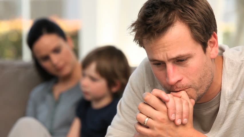 A man is worrying while his family is on the sofa