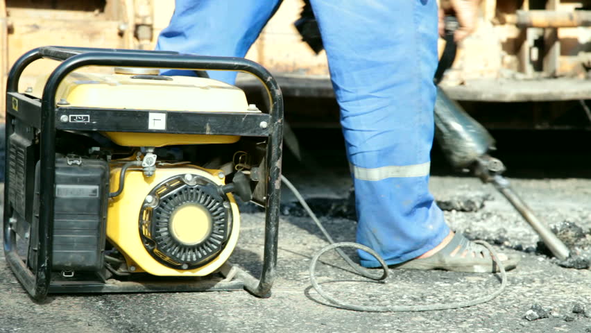 Road construction worker operates  pneumatic jack hammer