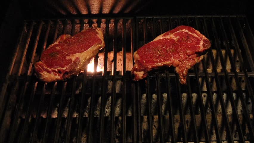 Red Rib Eye Steak on a barbecue grill being cooked