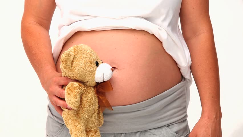 Pregnant woman holding a teddy bear isolated on a white background