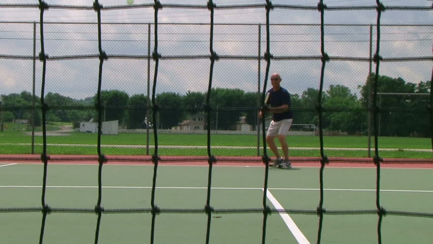 Tennis player volleys using forehand technique, crane shot from net.