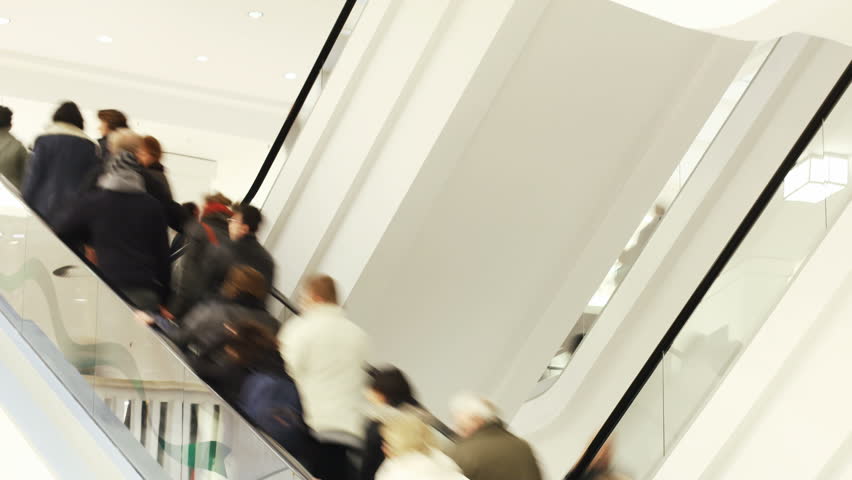People on fast moving escalator in public building  
