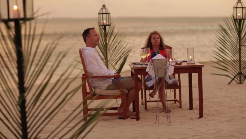 couple dining at sunset on a tropical beach 
