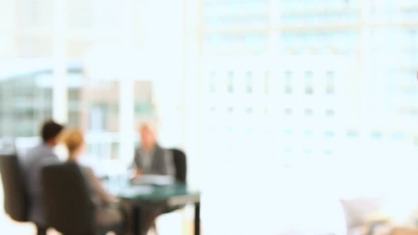 Businessman taking a phone call with business people in the background