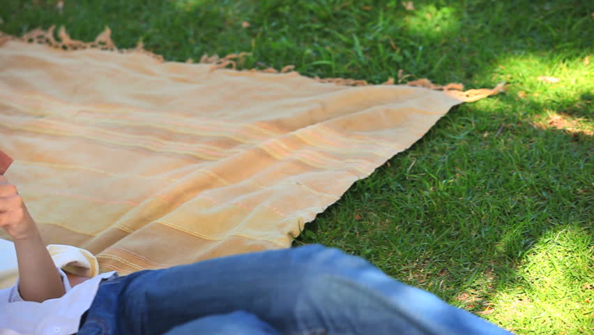 Man taking a nap while his girlfriend is reading a book in their garden