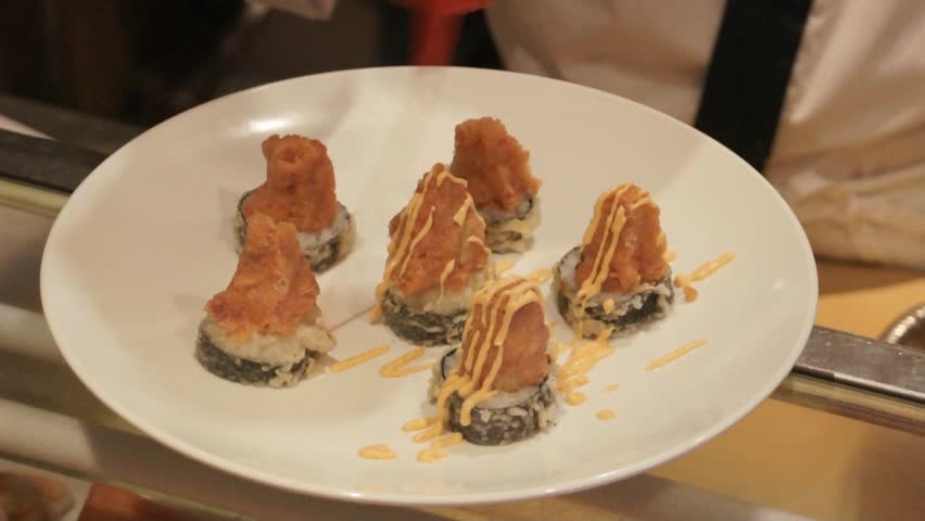 Chef making decorative spicy tuna appetizer at sushi restaurant.