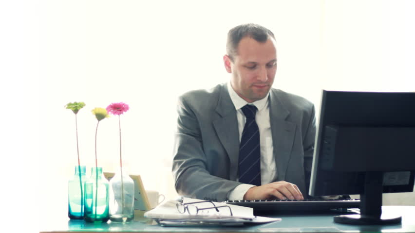 Businessman by the computer in the office showing ok sign