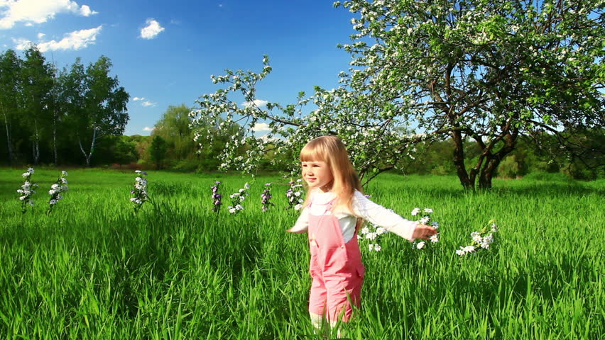 Smiling girl spinning in the grass. Dolly profile.