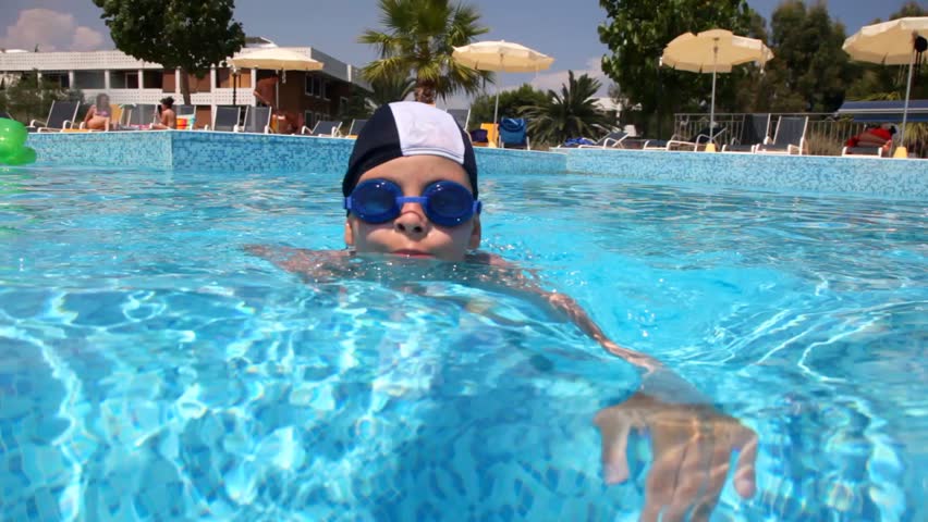 Boy in swimming goggles swimming in the pool water