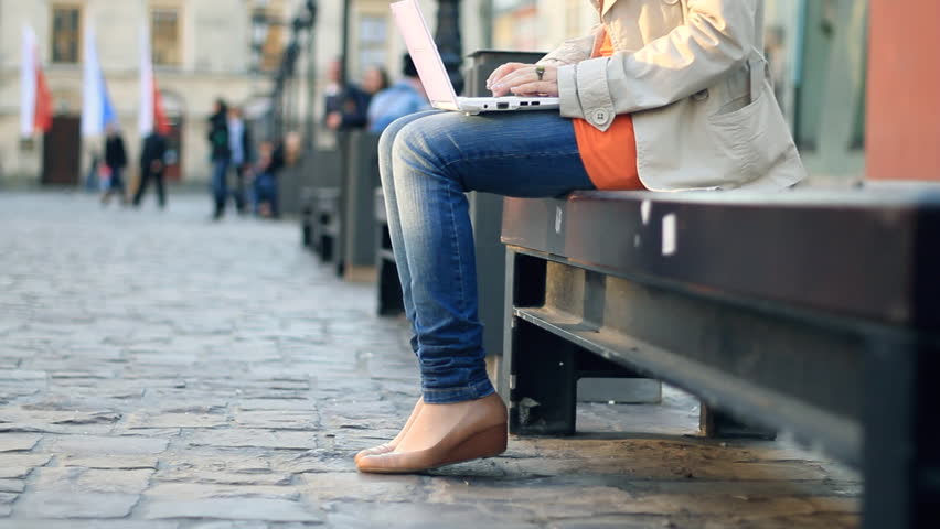 Woman with laptop sitting in urban environment, camera stabilizer shot