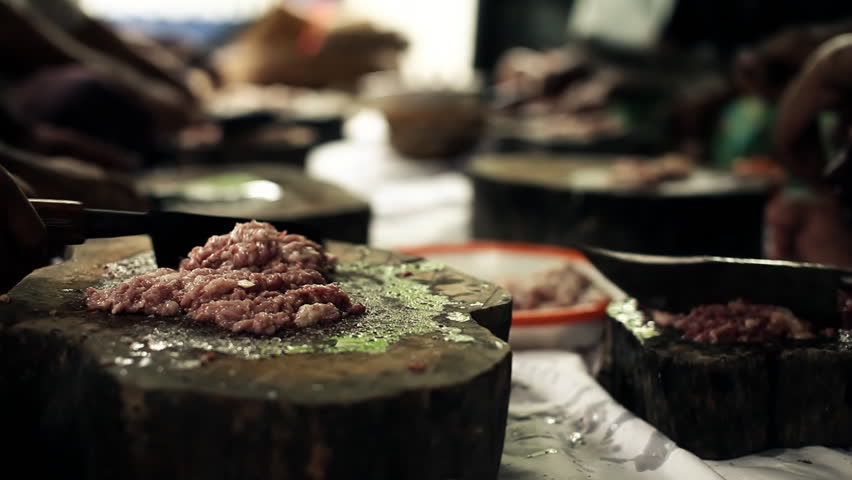 Group of indigenous balinese people sitting in a group and preparing meat for a big traditional celebration, atmospheric shot with selective focus 