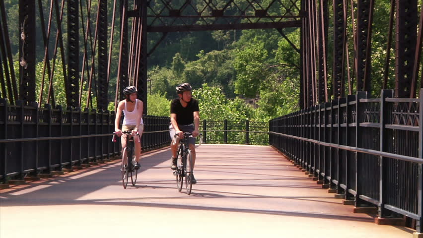 A young couple bike and sightsee on the bike trails on Washington's Landing, an island on the Allegheny River near Pittsburgh, Pennsylvania.