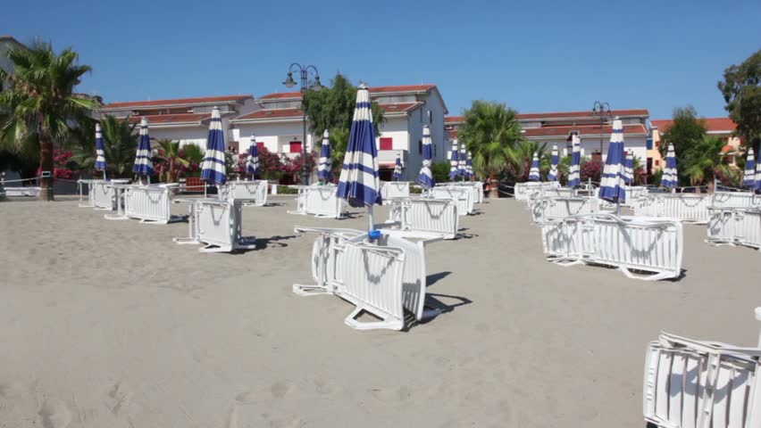 Young woman running away by sand between lot of deckchairs