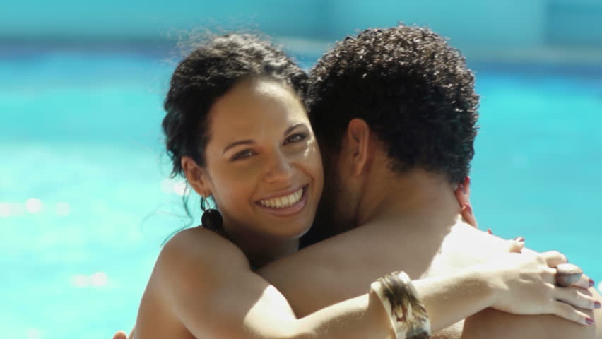 Honeymoon: happy young newlyweds smiling and relaxing near hotel pool 