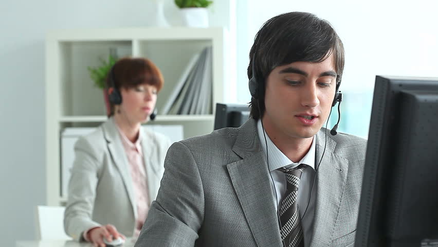 Handsome operator answering a call, then looking at camera and smiling