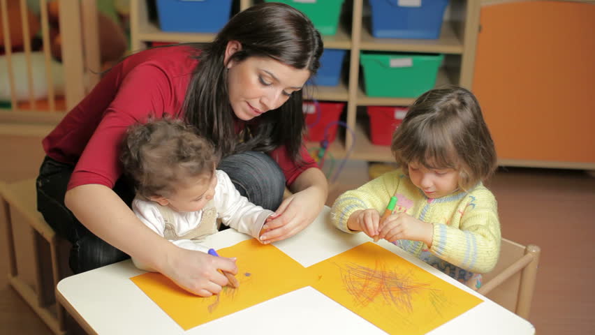 Preschool with teacher helping toddler and 2-3 year girl drawing