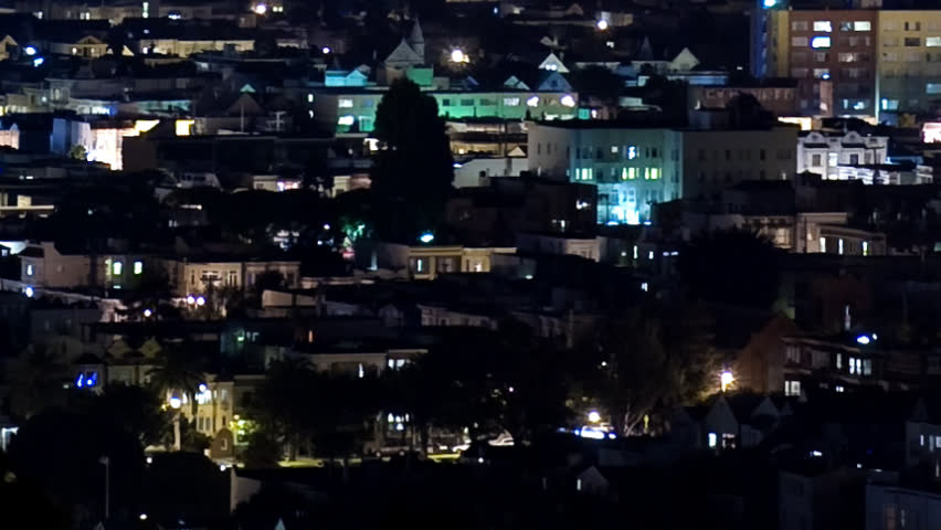 Time Lapse overhead of urban residential neighborhood at night. Camera pulls back revealing airplane lights streaking through turbulent clouds and landing at distant airport.