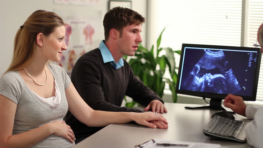 A young couple and a doctor look at an ultrasound