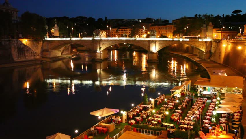 Cafe by the river, a number of people sitting at tables, passing cars on the Ponte Vittorio Emanuele II