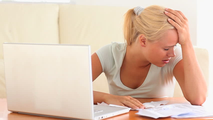 Depressed woman checking her expenses in her living room