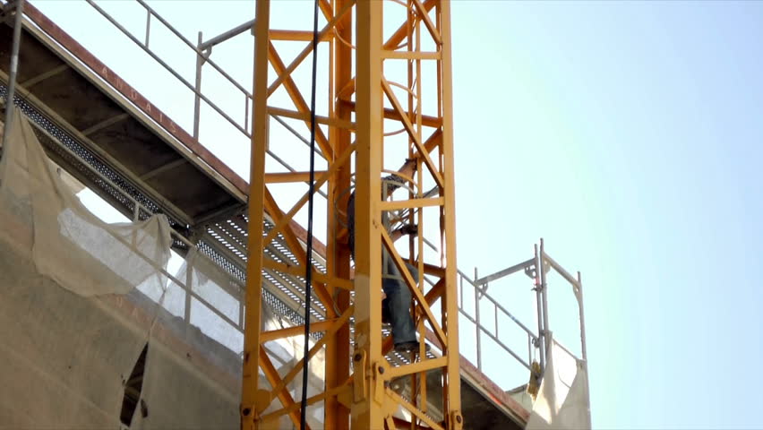 Man climbs ladder of construction crane.