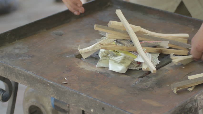Making fire on forge table with paper and wood 
