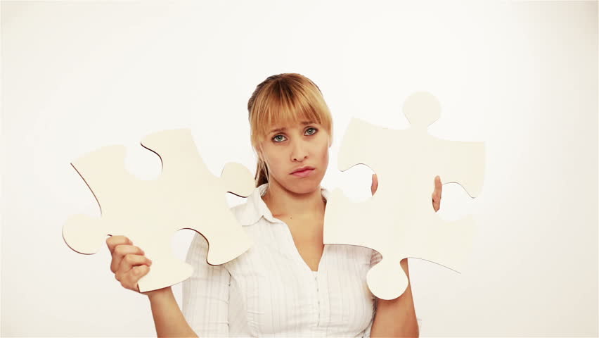 Frustrated young woman holding two oversized jigsaw pieces