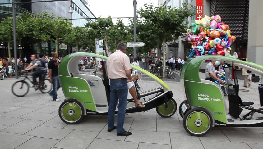 FRANKFURT GERMANY - JUNE 30: Pedestrians and human powered green ecological taxicabs outside shopping centers in Frankfurt, Germany March, June 30, 2011. 