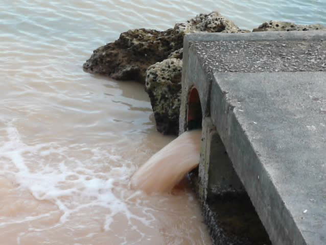 Sewage, waste or pollution gushing from a pipe into the sea next to a beach - no sound