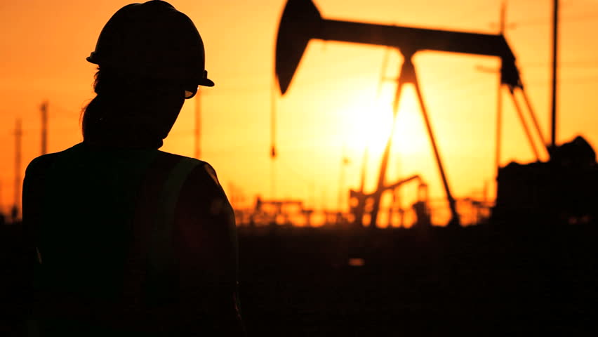 Female engineer using a cell phone at the site of a crude oil production farm