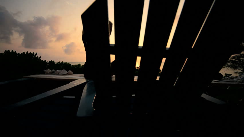 Slim athletic girl in silhouette practicing yoga overlooking the beach at sunrise