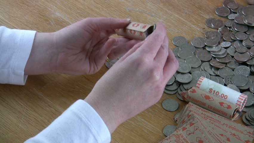 A woman filling a roll of quarters.
