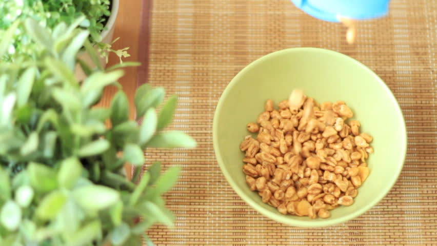 Pouring cornflakes into a bowl, slow motion, top view