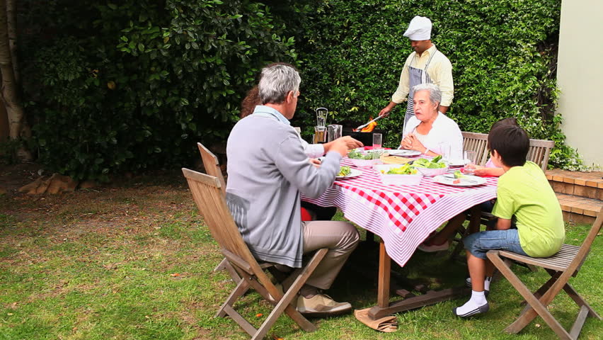 A husband is grilling at the family barbecue