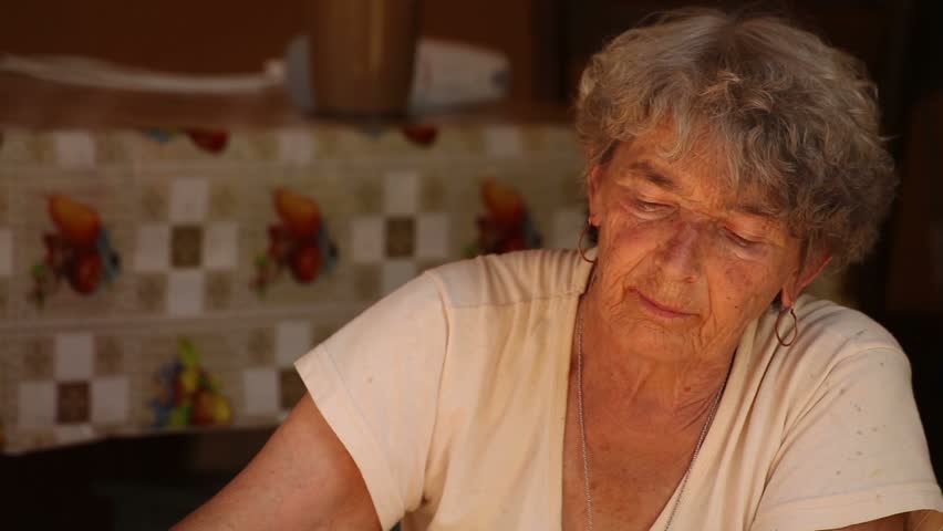 Farm tomato juice cooking. Old woman mixes and tries the juice. 