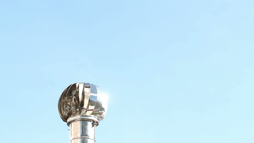 A view of a roof ventilator in motion against a brilliant blue sky