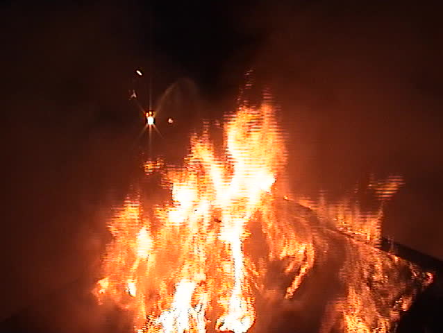 Structure fire at night with the structure engulfed in flames.