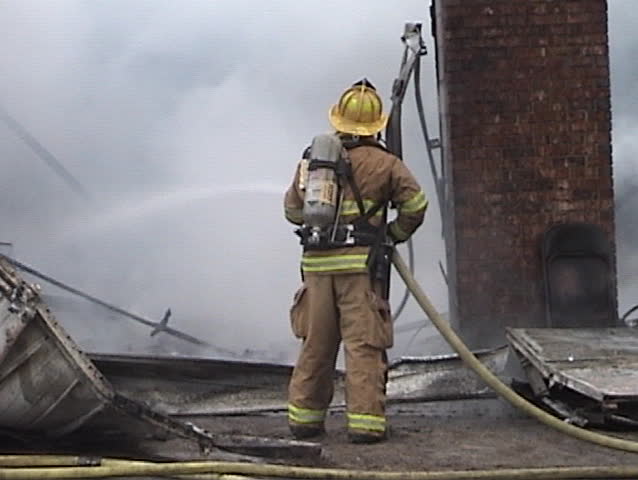 A firefighter hosing down hot spots.