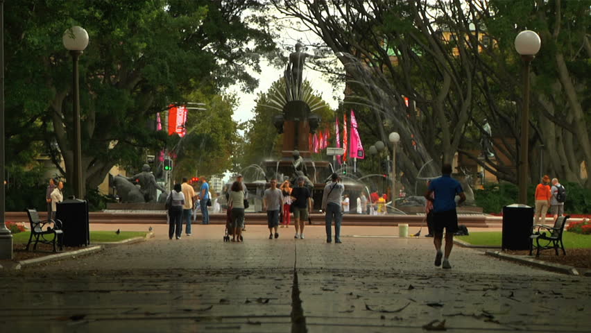 Sydney Hyde Park arch of trees low angle shot with people walking.