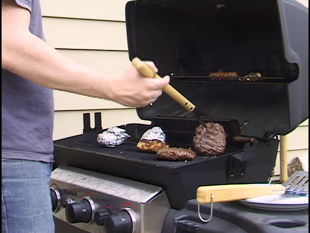 flipping burgers brats and chicken on grill