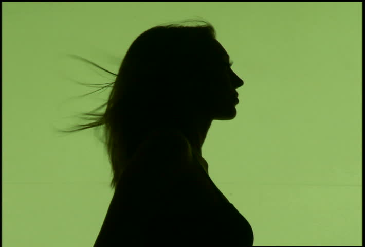 A silhouetted woman dancing against green background