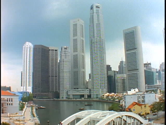 The skyline of Singapore rises above a bridge spanning a harbor.