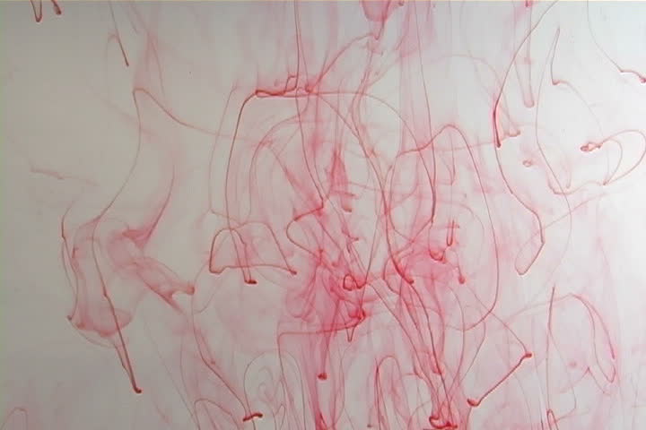 Red ink elegantly flowing in a liquified chamber.