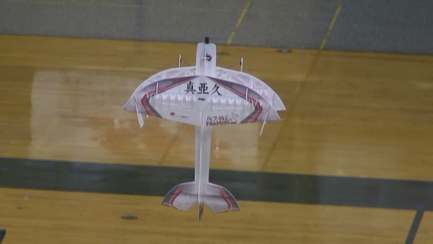 Radio-controlled foam model airplane performing aerobatic tricks at the competition venue