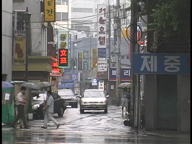 SEOUL, SOUTH KOREA - CIRCA 2010: Pedestrians and traffic travel through a rainy intersection circa 2010 in Seoul, South Korea.