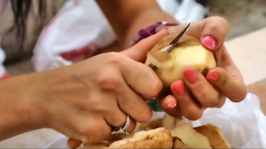 Young woman peeling potatoes close up