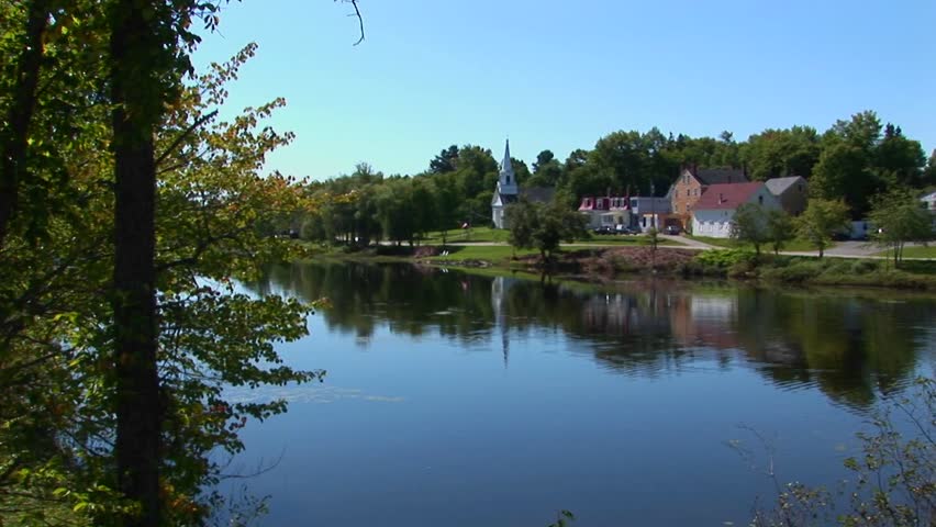 A lake reflects a peaceful countryside at a New England Maine town.