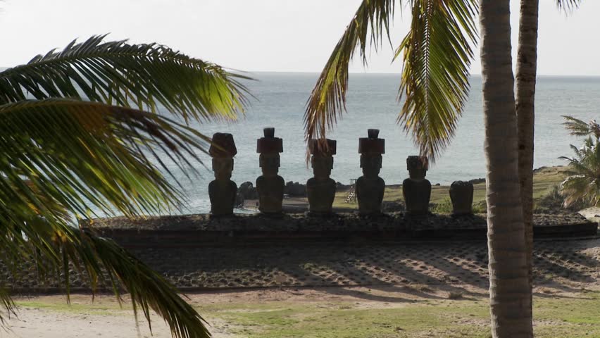 Easter Island statues with the ocean in the background and palms waving.